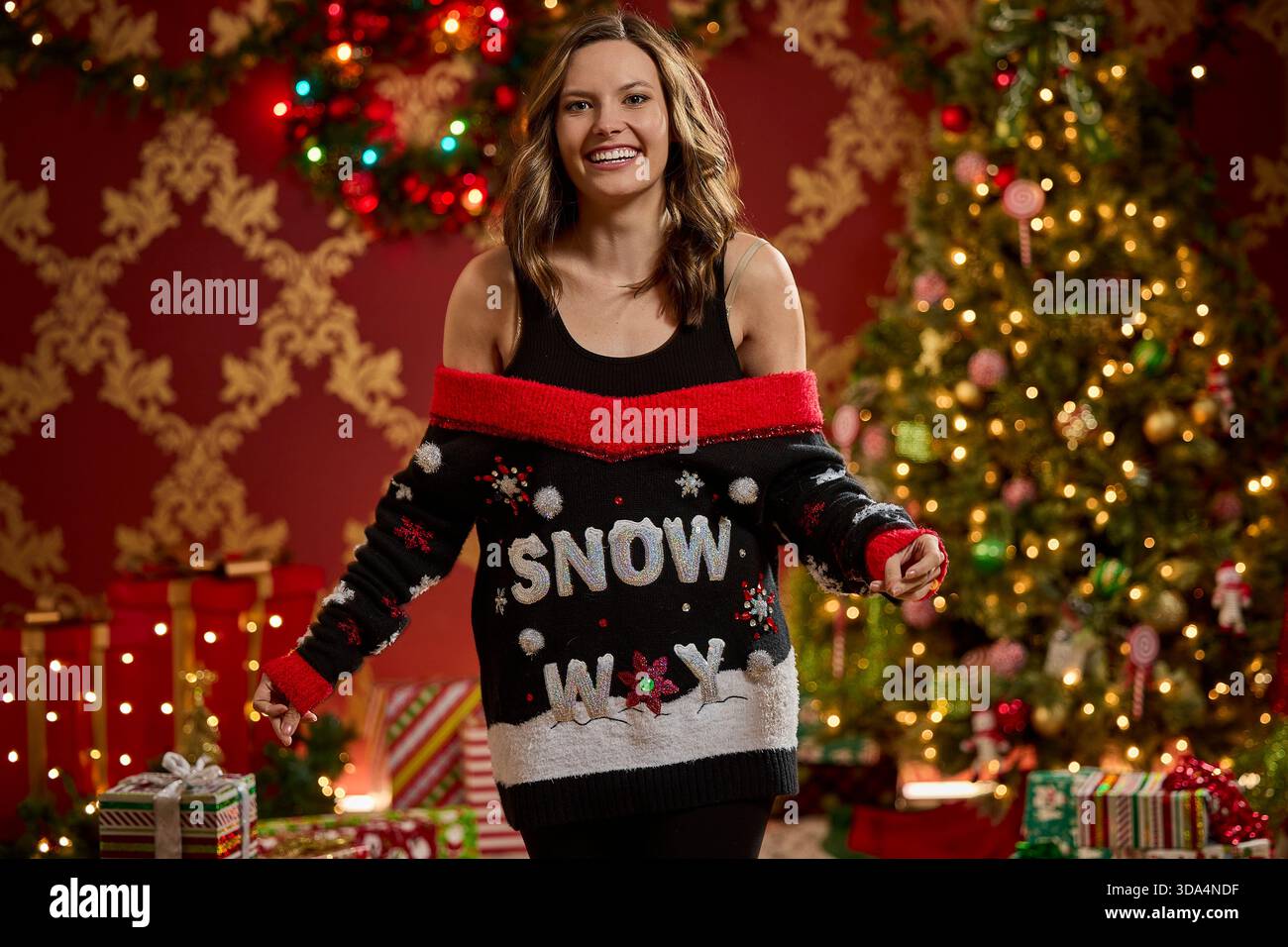 Donna che indossa un brutto maglione nero natalizio con motivo neve e dettagli rossi Foto Stock