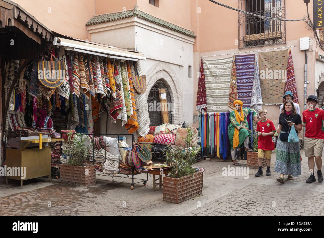 Piccola strada piena di tessuti colorati in un bazar marocchino circondato dai visitatori Foto Stock