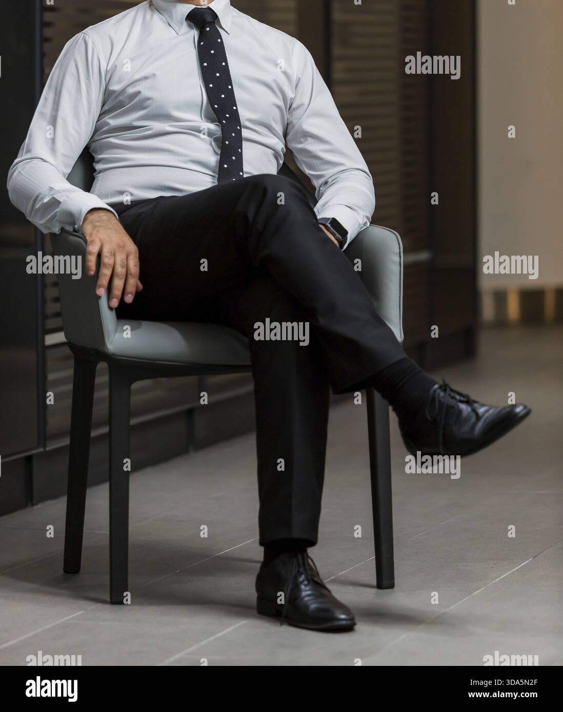 Testa mozzata uomo in un elegante abito camicia e cravatta in una sedia da ufficio Foto Stock