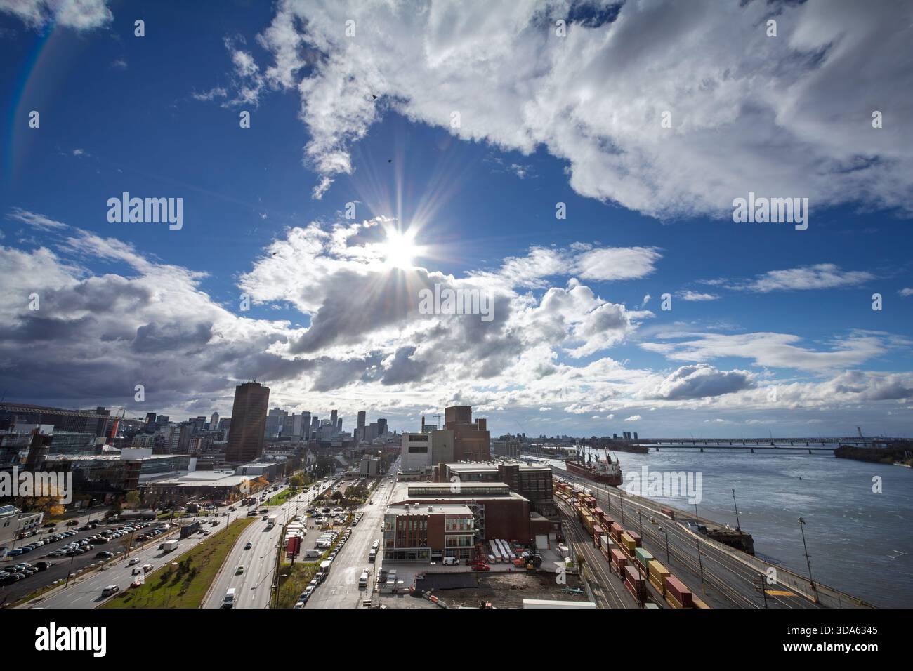 Ampia vista del porto industriale di Montreal sul fiume San Lorenzo in canada, con cantieri ferroviari, container impilati e una nave da carico, con skyline del centro Foto Stock