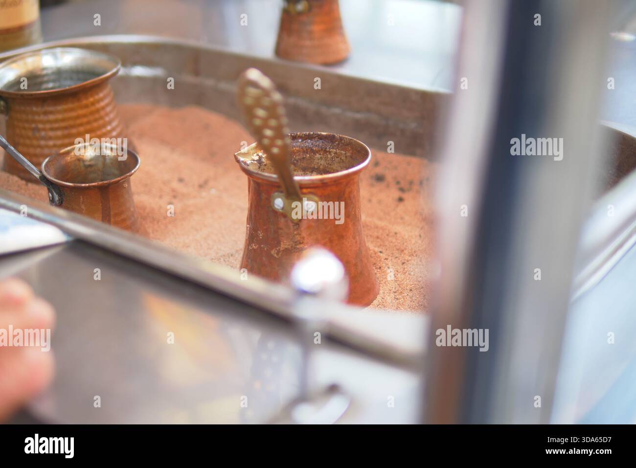 Preparare caffè turco con pentole di rame in una cucina affollata Foto Stock