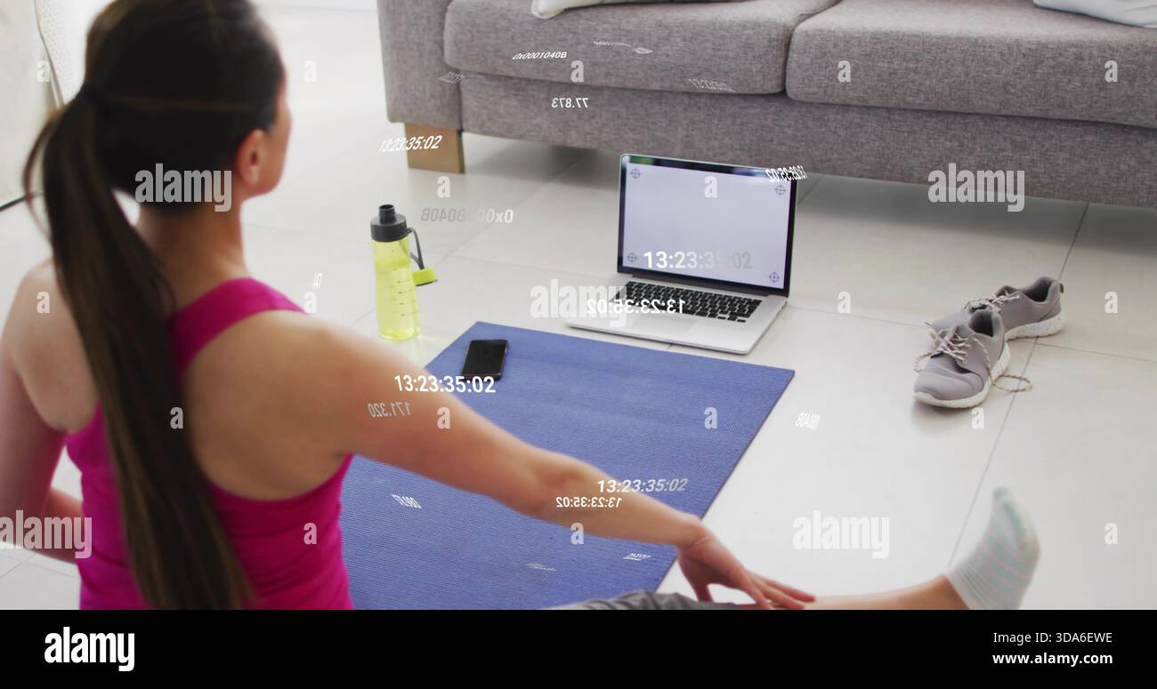 Donna che si allunga indossando abiti da ginnastica su un tappetino blu a casa con laptop e smartphone, spazio per copiare Foto Stock