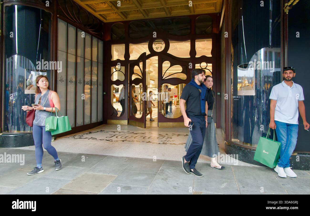 Iconica famosa attrazione turistica Harrods Shop ingresso n. 7 porte con shopping che porta borse Knightsbridge Londra Inghilterra Regno Unito Europa Foto Stock