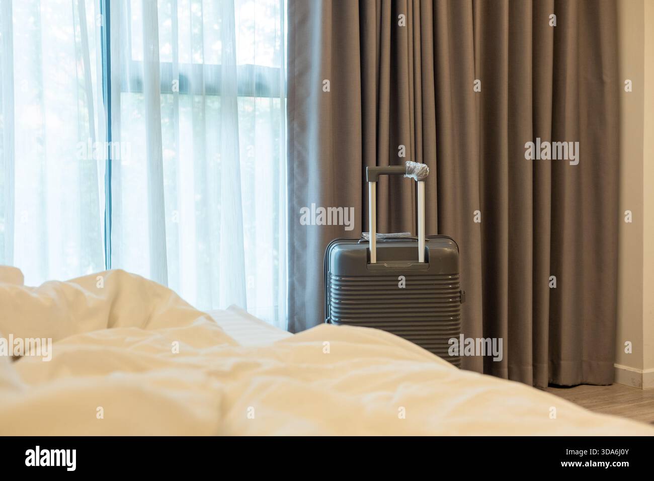 Grandi bagagli posizionati accanto al letto della camera da letto, che mettono in risalto lo stile di vita e la pianificazione rilassata del viaggio Foto Stock