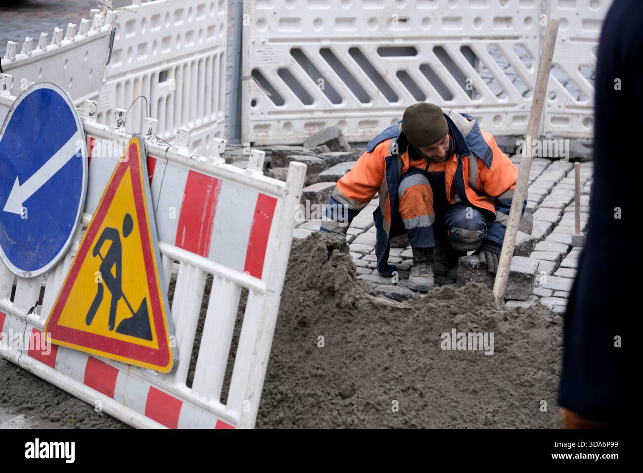 Un lavoratore esperto posiziona con cura il cemento fresco in una strada trafficata. Kiev, Ucraina. 8 dicembre 2025. Foto Stock