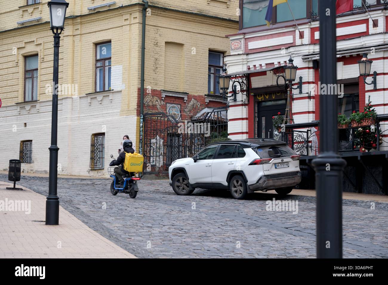 I motociclisti che effettuano consegne viaggiano lungo un'affascinante strada del vecchio mondo. Kiev, Ucraina. 8 dicembre 2025. Foto Stock