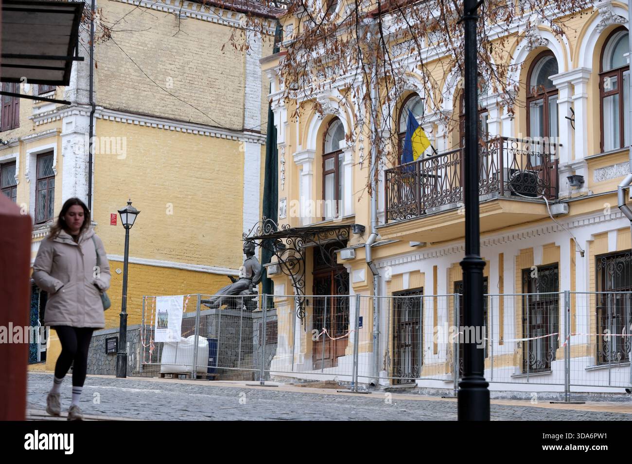 Una donna passeggia davanti a un'incantevole architettura antica in una pittoresca strada Ucraina. Andreevsky Uzviz, Kiev, Ucraina. 8 dicembre 2025. Foto Stock
