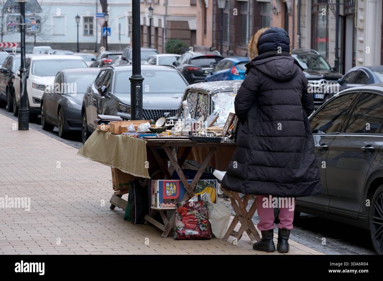 Una donna naviga in un mercato all'aperto, esplorando oggetti unici in una giornata fredda. Andreevsky Uzviz, Kiev, Ucraina. 8 dicembre 2025. Foto Stock