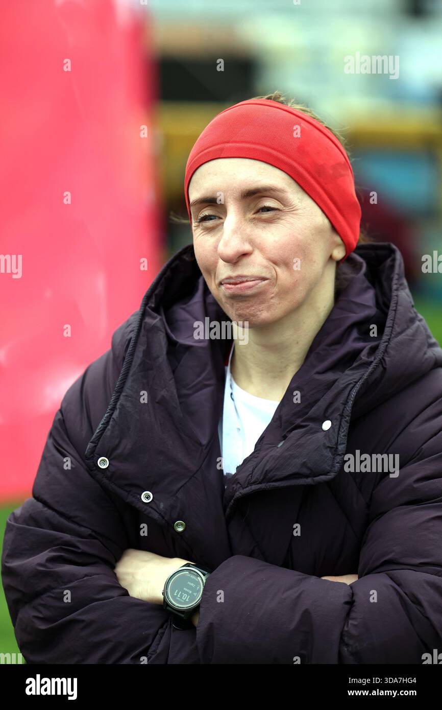 Donna con una giacca a piumino e fascia rossa con un'espressione sottile Foto Stock