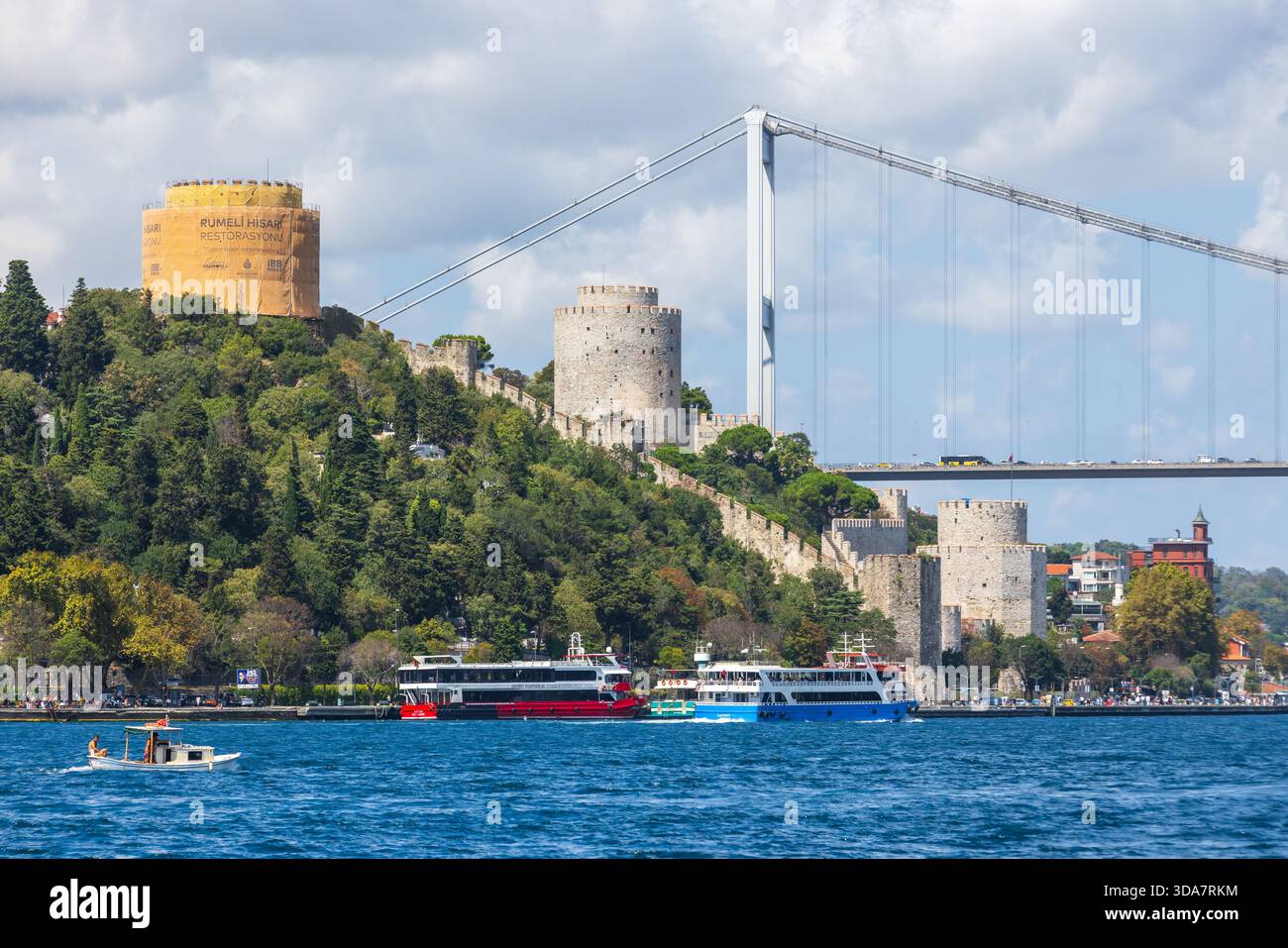 Istanbul, Turchia - 24 agosto 2025: Un vivace lungomare lungo il Bosforo in una giornata di sole, torri storiche della fortezza rumeliana e navi passeggeri, Foto Stock