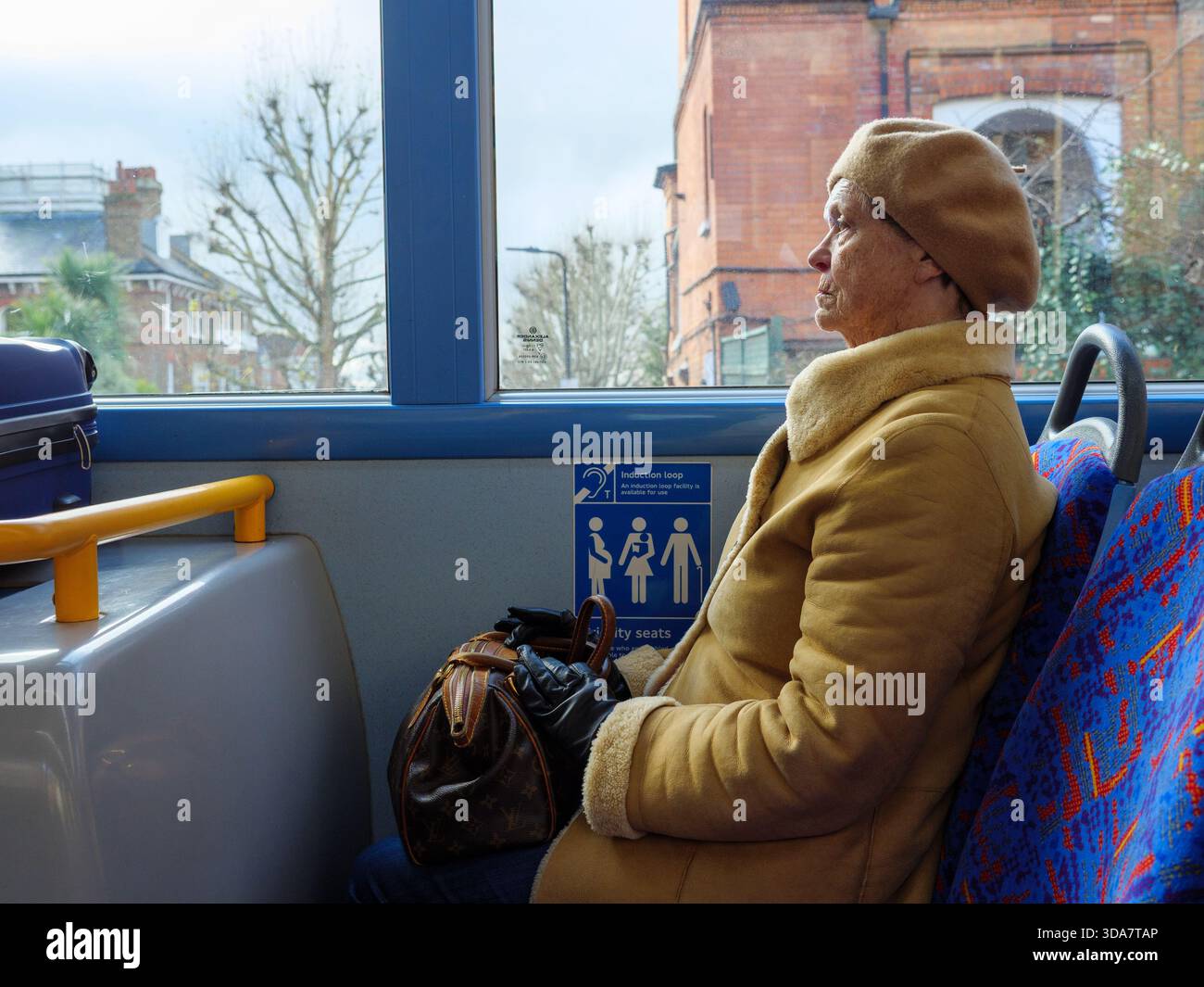 Donna anziana passeggero seduto in posti prioritari di un autobus di Londra, Inghilterra, Regno Unito Foto Stock