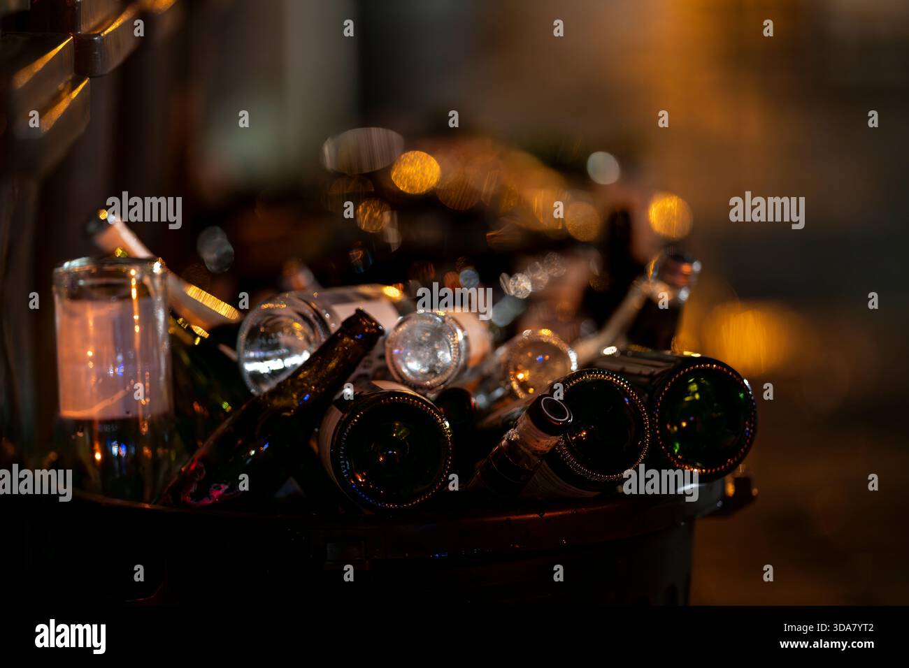 Pile di bottiglie di vetro vuote di notte con calde luci bokeh sullo sfondo. Bottiglie di vino scartate per creare un ambiente urbano tranquillo. Foto Stock