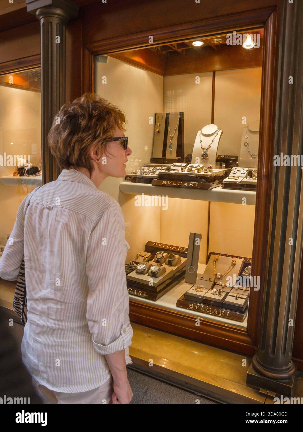 Shopping di lusso in Italia, vista posteriore di una donna che guarda una mostra di gioielli Bulgari in un negozio situato sul Ponte Vecchio a Firenze, Italia Foto Stock
