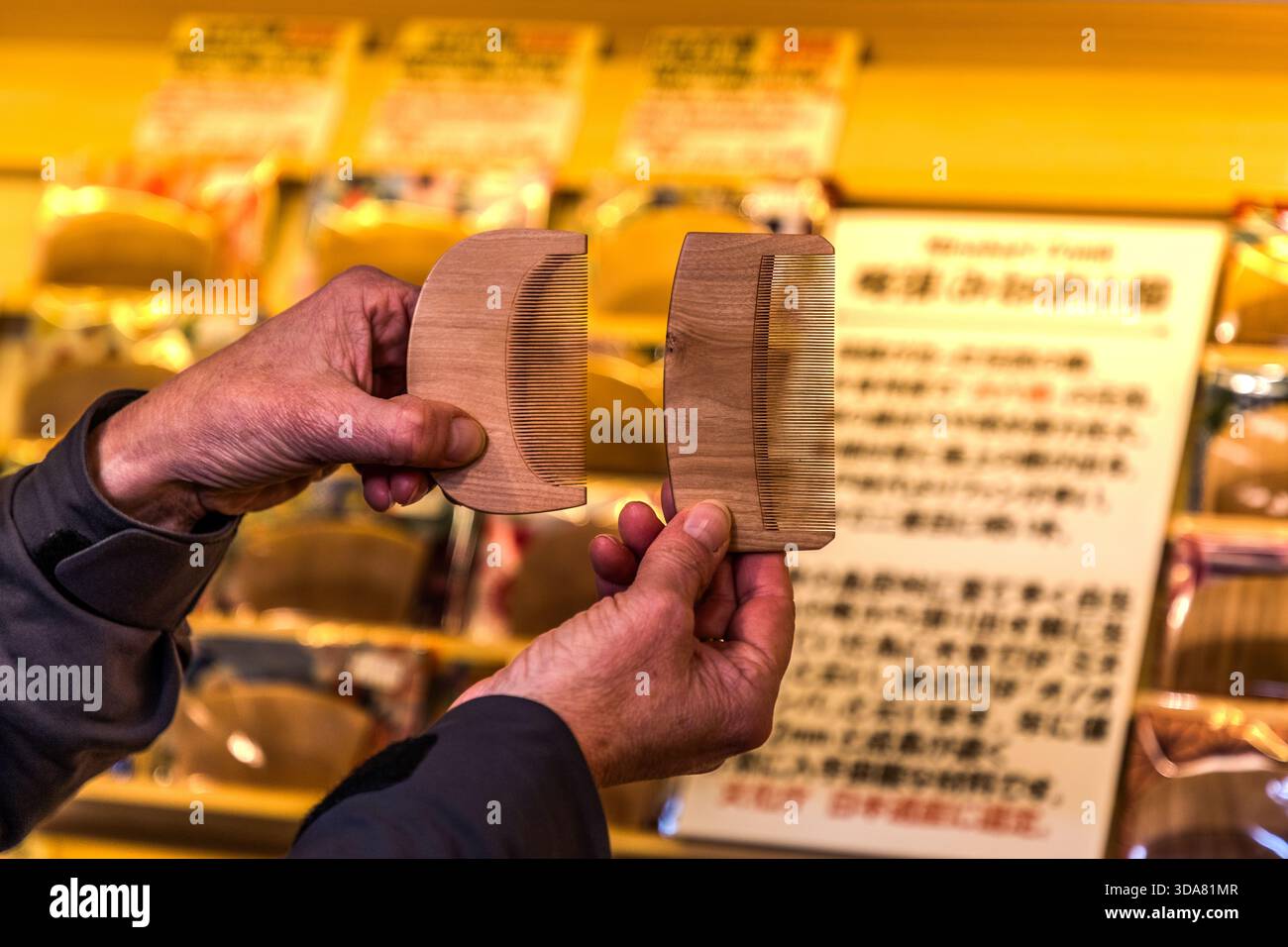 Due pettini in legno artigianali della regione di Kiso sono esposti in un negozio presso la stazione postale di Nakasendo, Narai-juku; dietro le mani c'è un cartello informativo in giapponese. Narai, Shiojiri, Prefettura di Nagano, Giappone Foto Stock