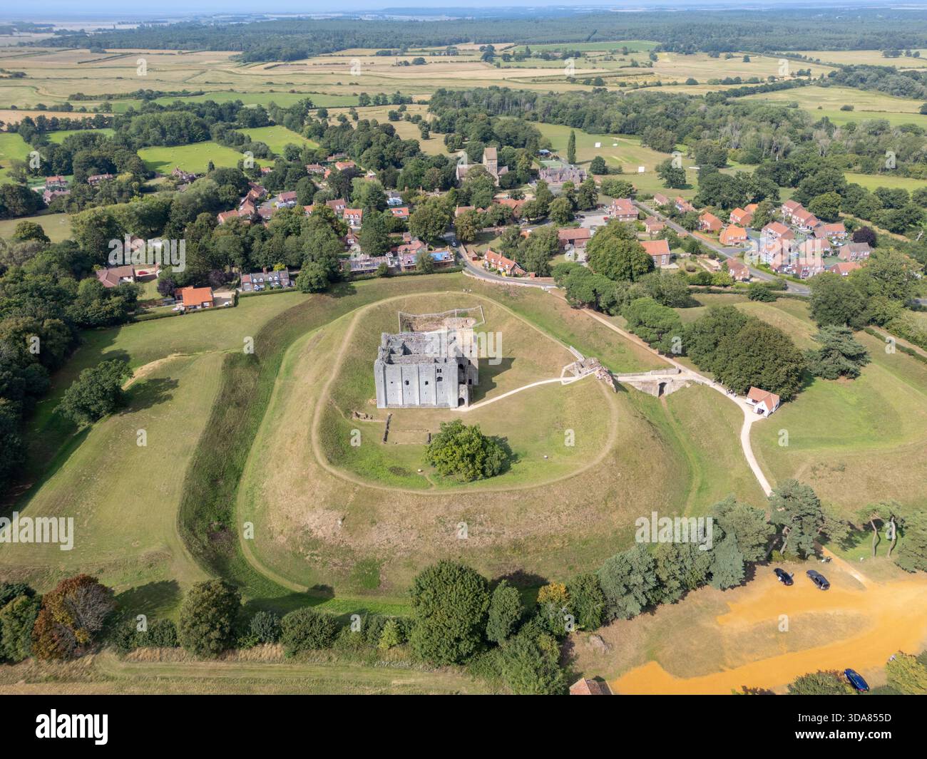 La vista aerea delle rovine di pietra di Castle Rising si erge orgogliosamente in cima al suo tumulo erboso, incorniciato dal pittoresco villaggio e dai vasti campi aperti dietro, King's Foto Stock