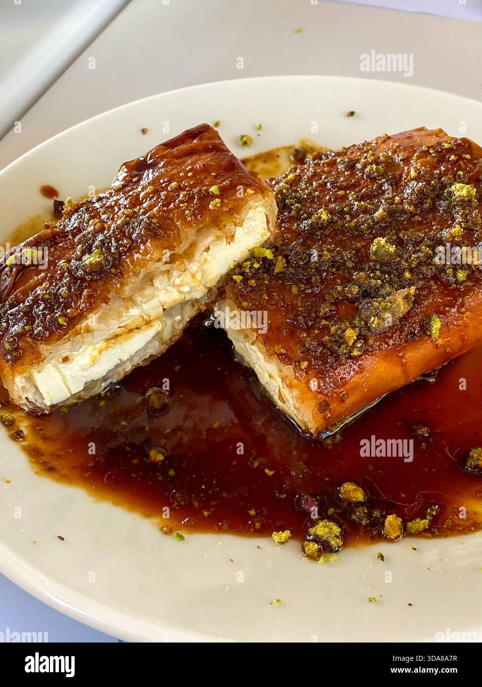 Primo piano di feta grigliata con sciroppo di miele e pistacchi schiacciati, con crosta dorata e glassa ricca. - Immagine stock catturata con smartphone