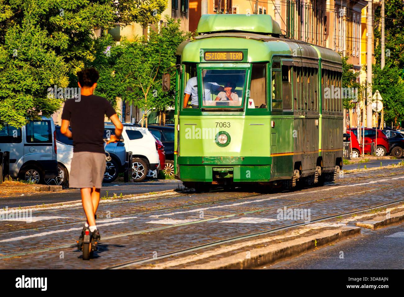 Adolescente su uno scooter elettrico lungo i binari del tram in via di porta maggiore, Roma, Italia. Foto Stock