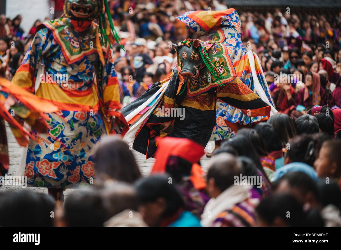 Thimphu, Bhutan - 28 settembre 2025: Veduta di vibranti ballerini mascherati in costumi colorati, esibendosi al festival Thimphu Dromchoe in mezzo a un mare di Foto Stock
