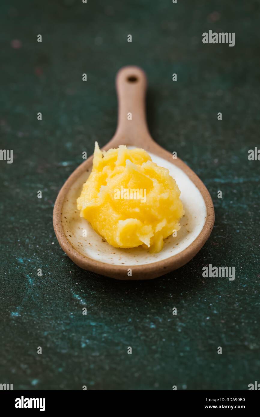 Ghee senza lattosio, in cucchiaio piccolo su sfondo scuro, cucina sana Foto Stock