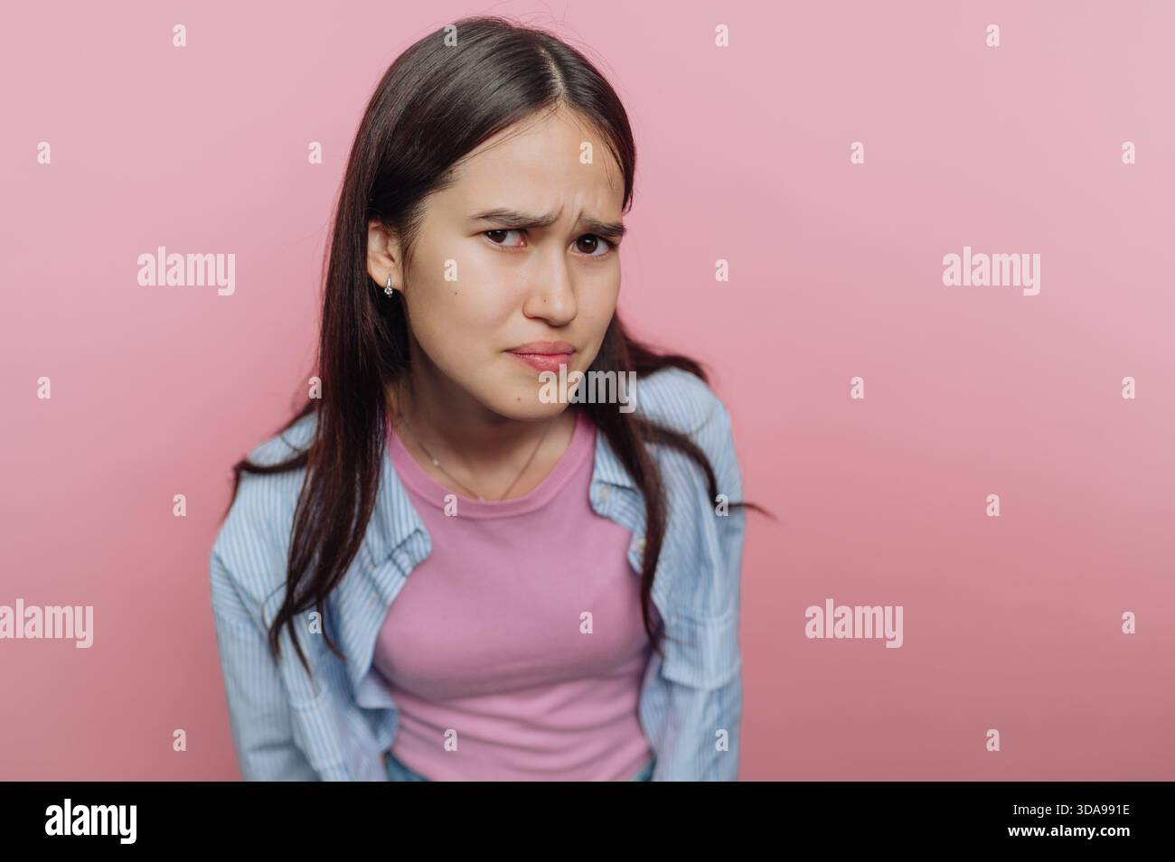Giovane donna con un'espressione scettica su sfondo rosa. Foto Stock