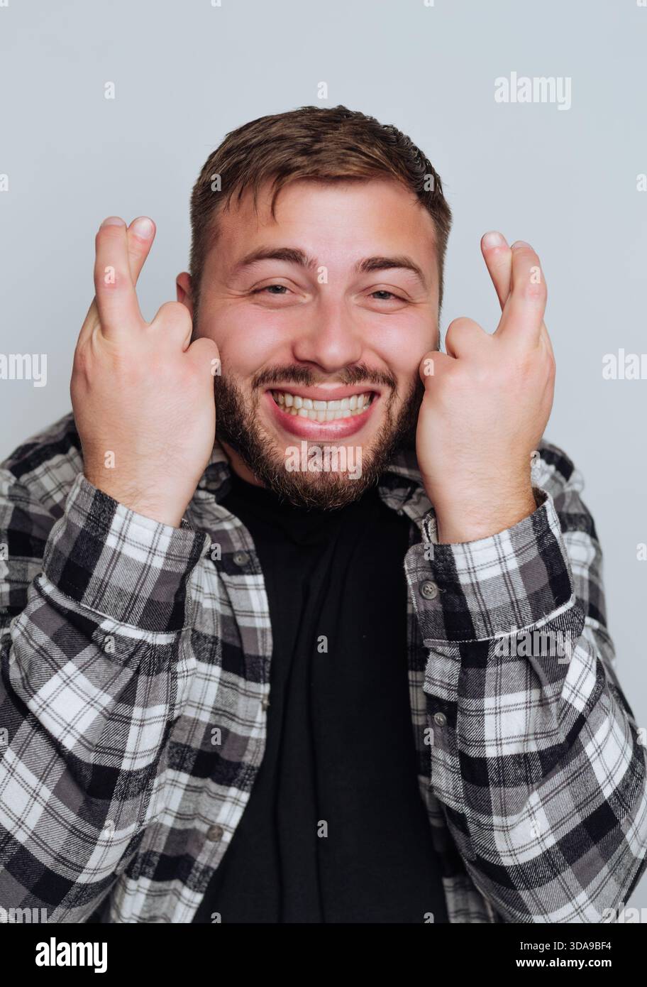Uomo sorridente con le dita incrociate che indossa una camicia a quadri. Foto Stock
