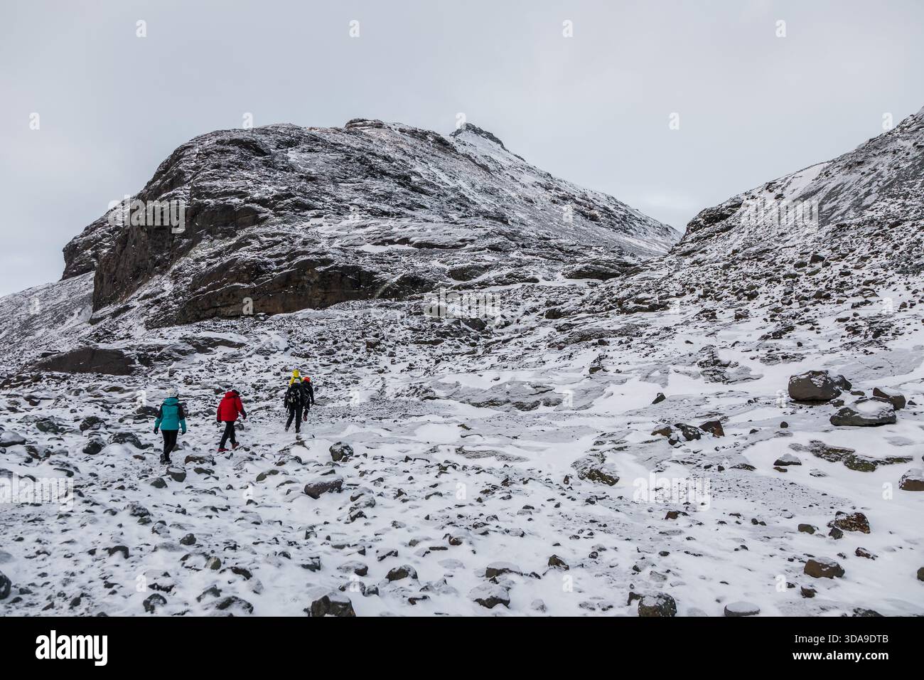 Islanda, 2 febbraio 2022 — Un gruppo di escursionisti attraversa una valle rocciosa e innevata in avvicinamento alla Grotta di ghiaccio blu vicino a Vatnajokull Foto Stock