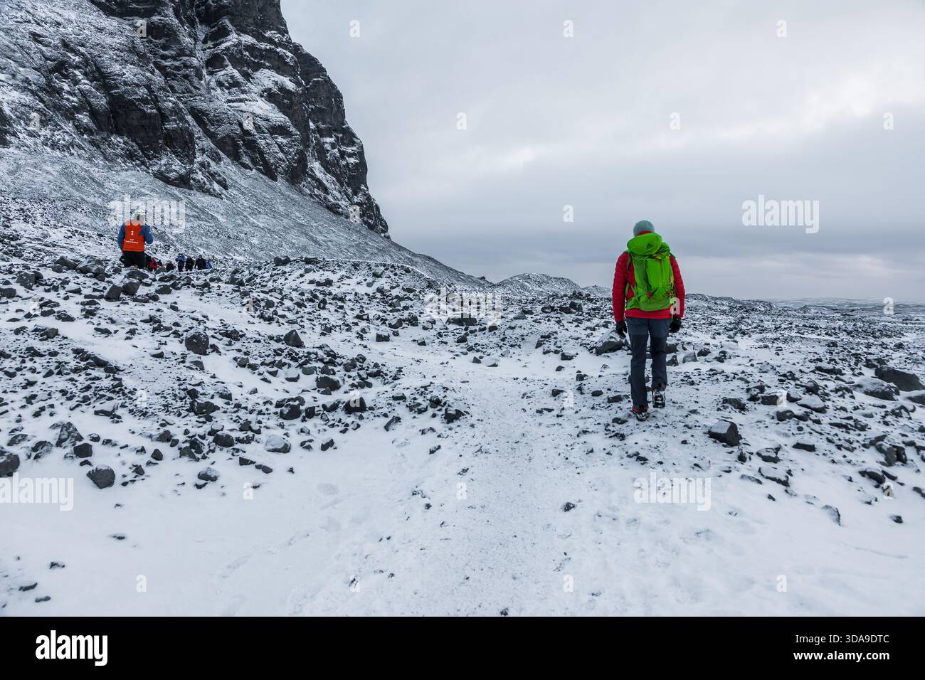 Islanda, 2 febbraio 2022 — Un gruppo di escursionisti attraversa una valle rocciosa e innevata in avvicinamento alla Grotta di ghiaccio blu vicino a Vatnajokull Foto Stock