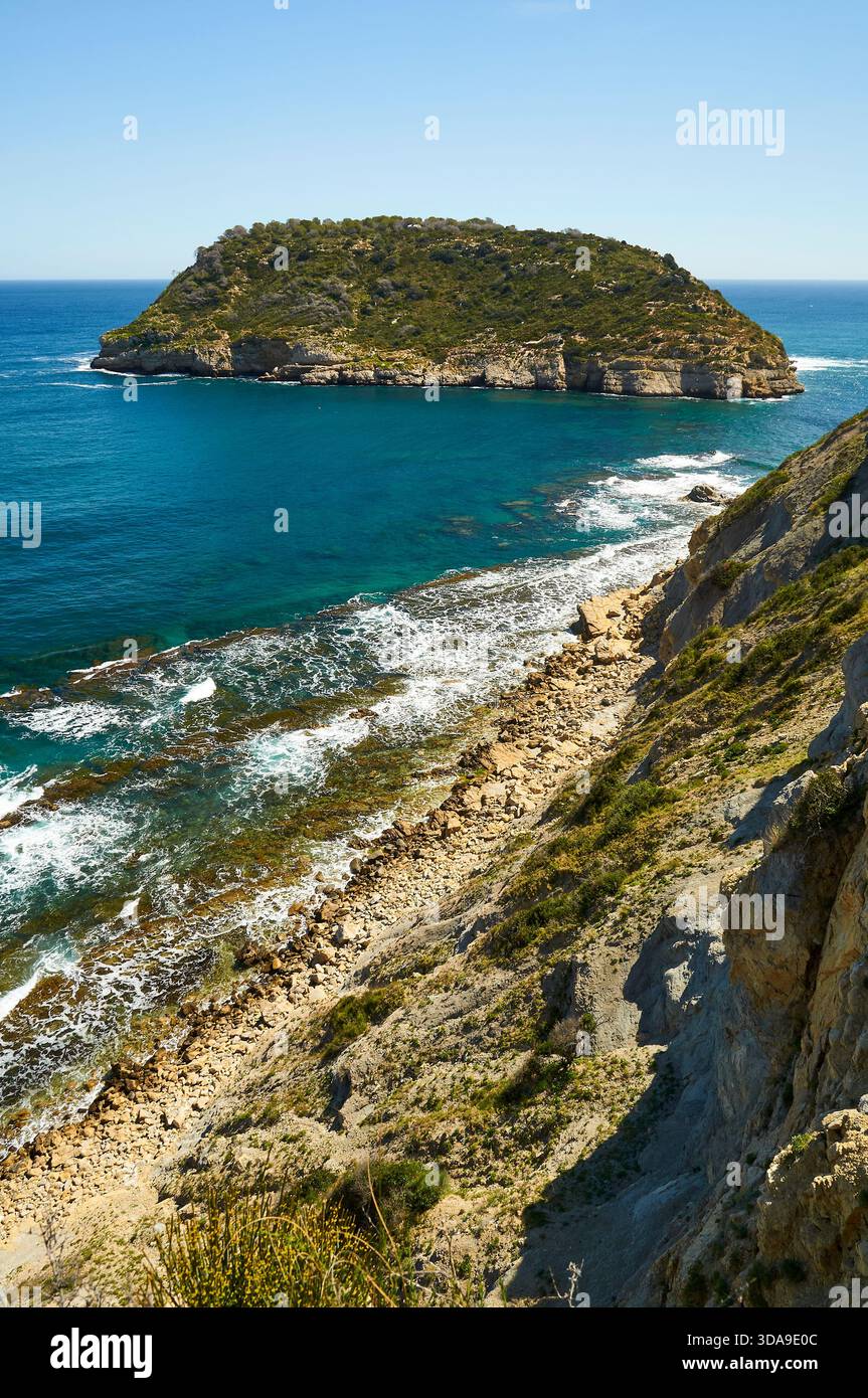 Isola dell'Isla del Portitxol e onde che si infrangono sulla riva dalle scogliere della spiaggia di Portichol (Jávea, Marina alta, Alicante, Mar Mediterraneo, Spagna) Foto Stock