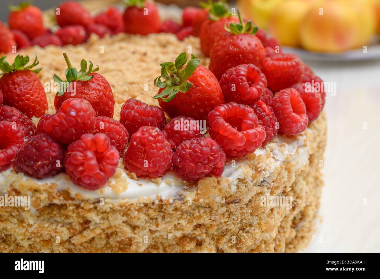 Primo piano di un dolce dolce dolce dolce e multistrato di torta a strati con ripieno cremoso e lamponi vivaci serviti su Un piatto bianco Foto Stock