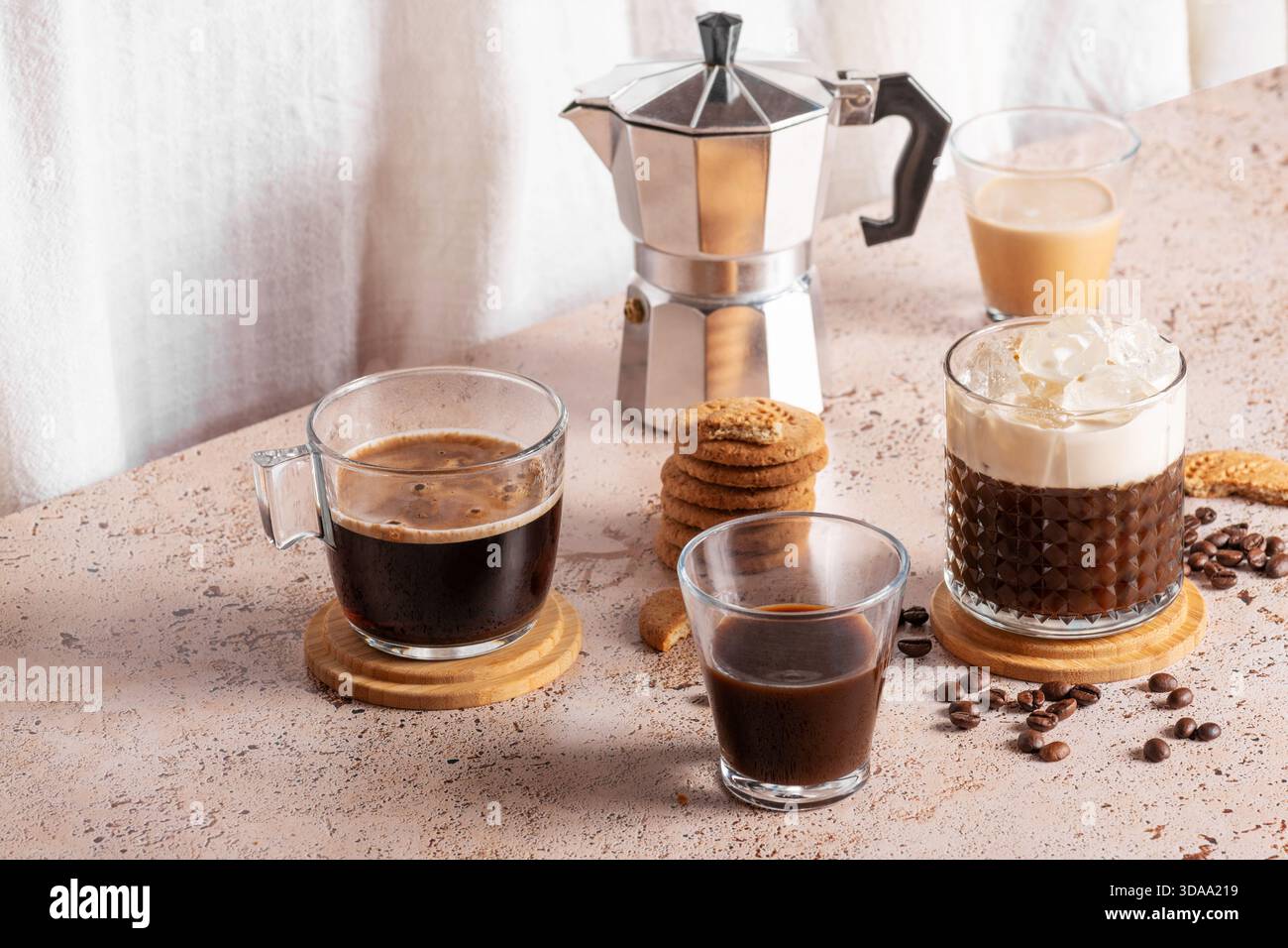 Espresso appena fatto, caffè freddo e moka in un ambiente accogliente e beige. Diversi tipi di bevande al caffè con biscotti su un tavolo beige Foto Stock
