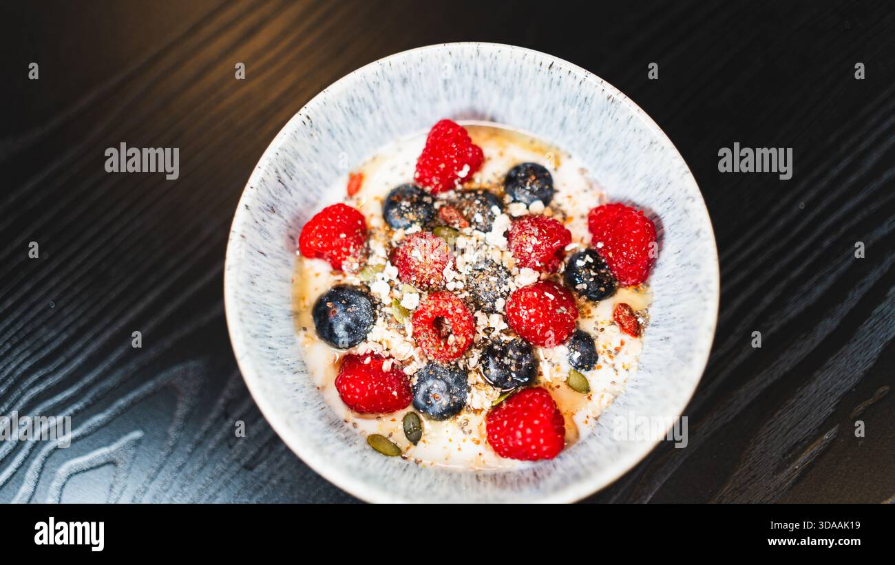 Sana ciotola di yogurt con lamponi e mirtilli freschi. Colazione o spuntino nutriente e ricco di antiossidanti per uno stile di vita attivo ed equilibrato Foto Stock