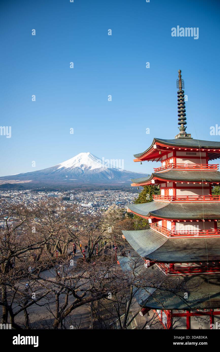 Pagoda di Chureito con il Monte Fuji e Fujiyoshida sotto. Composizione verticale che mostra la pagoda rossa accanto al Fuji innevato che si affaccia sulla città. Foto Stock