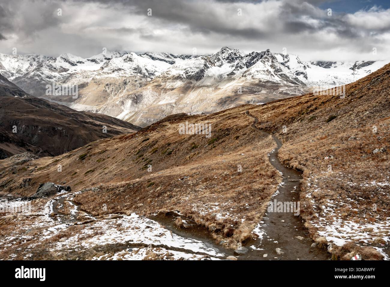 Lo stretto sentiero emerge dalla neve nelle Alpi svizzere sotto il Cervino Foto Stock