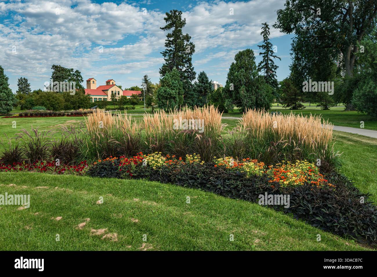Un letto da giardino al City Park di Denver, Colorado, con piante di Reed Grass, Zinnias e Black Pearl Pepper e il Pavilion, punto di riferimento dell'edificio. Foto Stock