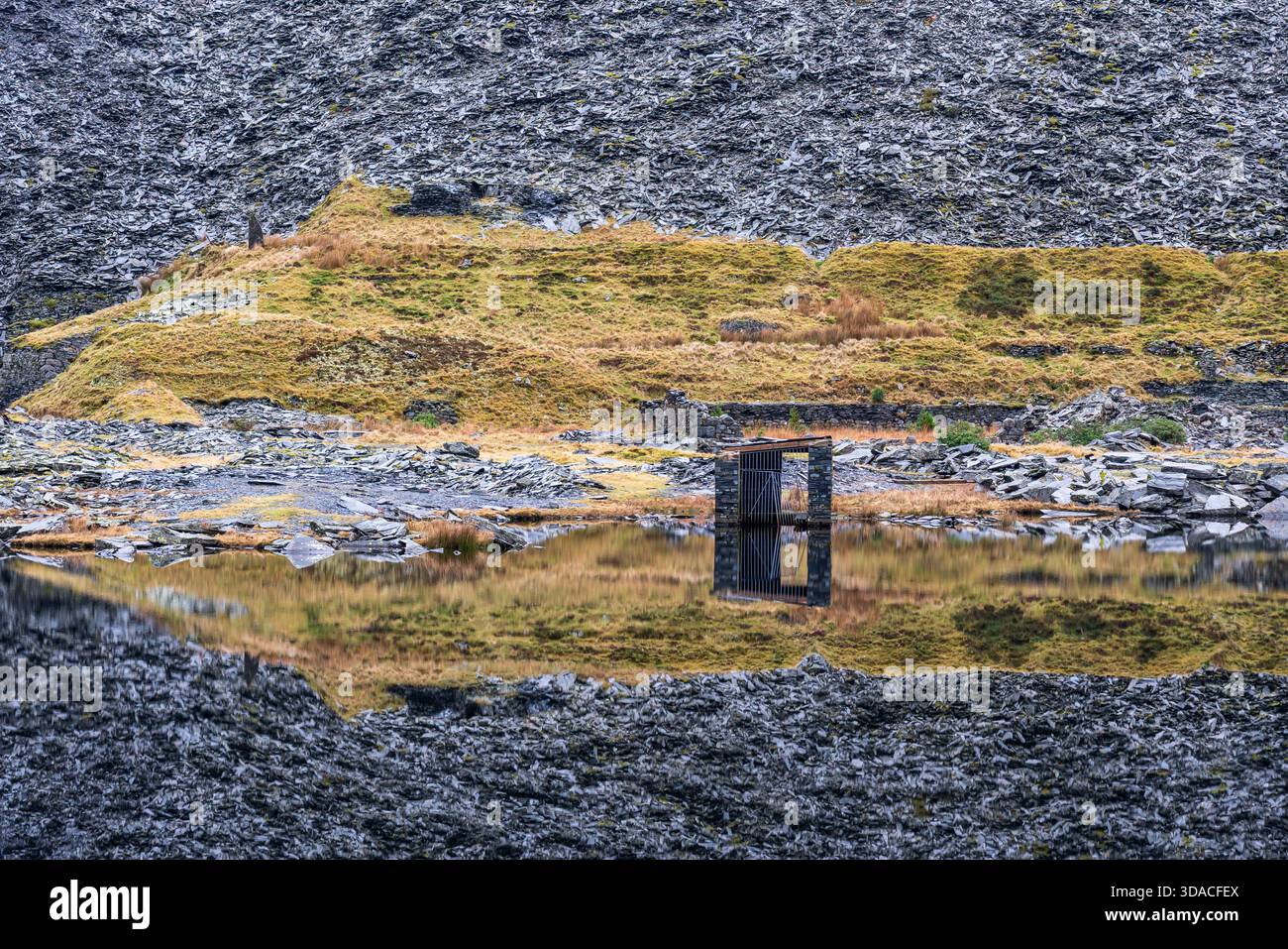 Piccola struttura in pietra riflessa in Llyn Cwmorthin a Cwmorthin Slate Quarry in Snowdonia Foto Stock