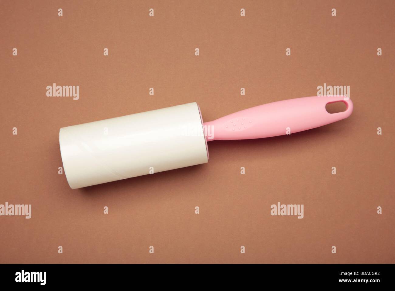 Spazzola a rullo per tessuti con panno e rullo di lanugine con rotolo di carta su sfondo marrone. Spazio per il testo Foto Stock