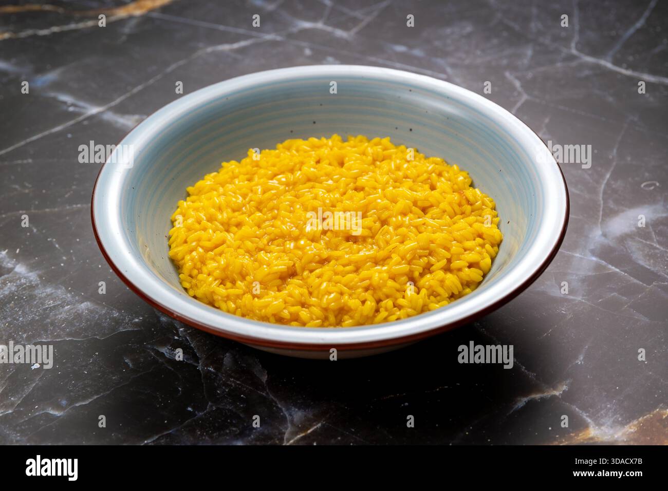 Risotto allo zafferano giallo che presenta un'autentica specialità culinaria italiana Foto Stock