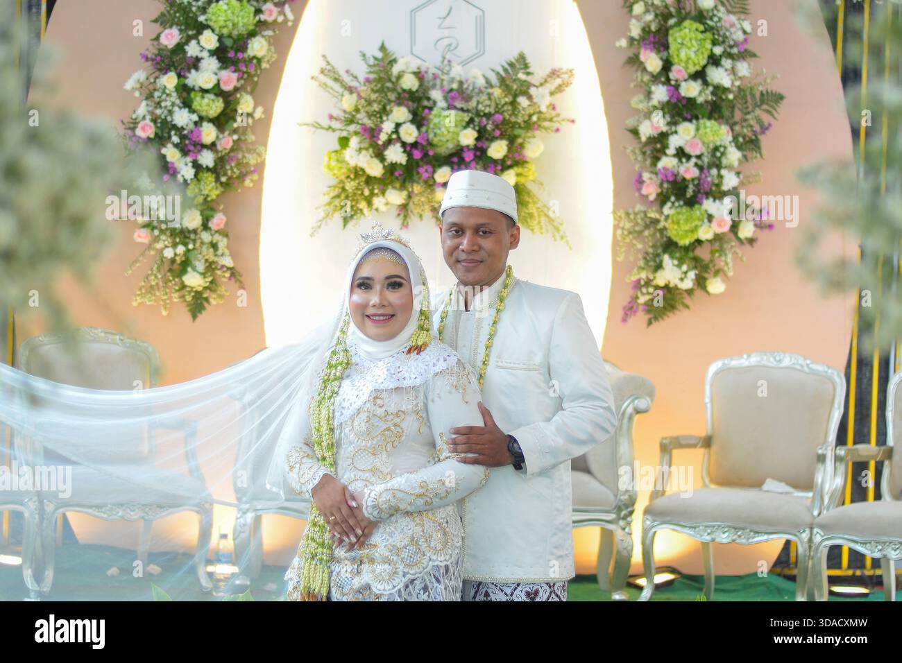 Una posa da sposa e sposo di fronte a un altare decorato in modo luminoso Foto Stock