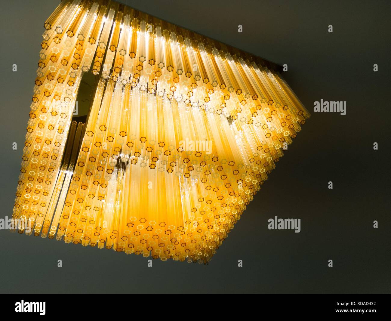 Elegante lampadario in vetro giallo sospeso dal soffitto che illumina gli interni moderni con una calda luce soffusa Foto Stock