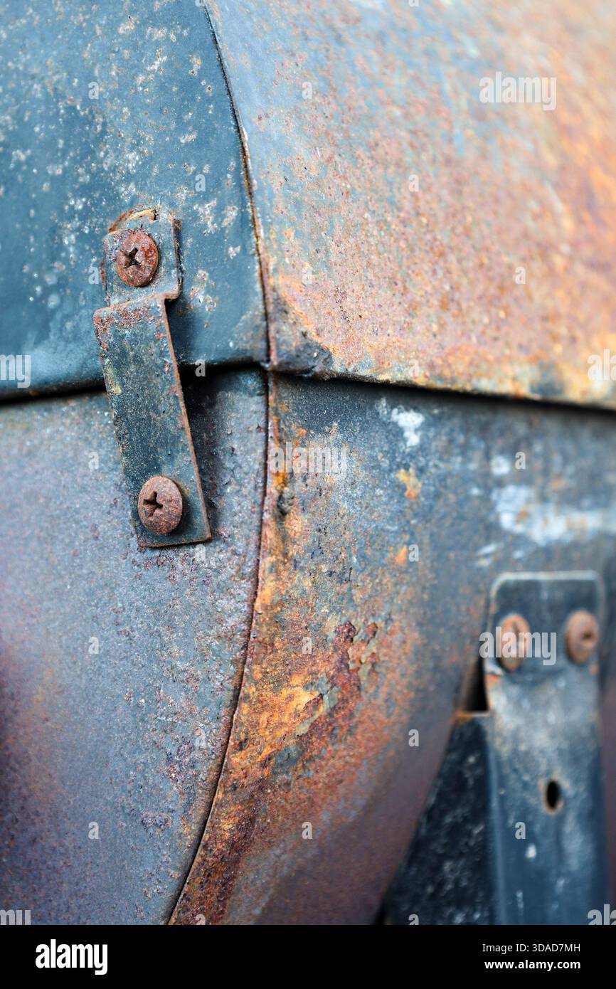 Primo piano dettagliato di una superficie metallica fortemente arrugginita con viti corrose, strati di pelatura e ricchi colori patina Foto Stock