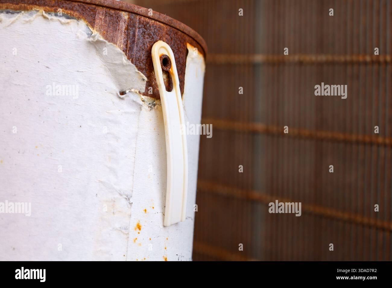 Vista ravvicinata di una bomboletta di vernice arrugginita con manico usurato, carta da peeling e texture industriali Foto Stock