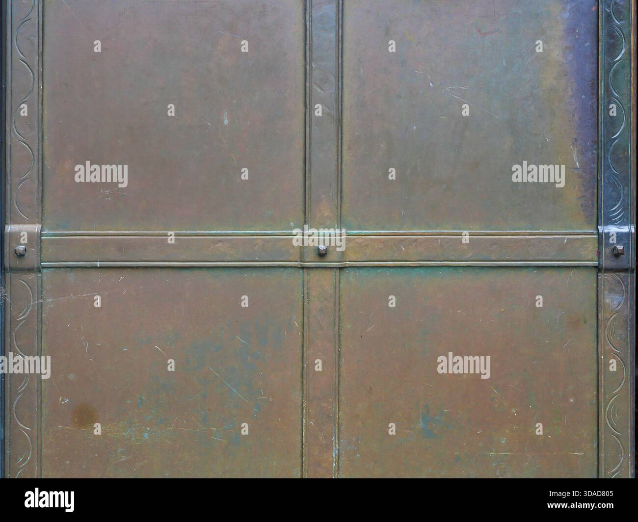 Dettaglio di una superficie metallica color bronzo con struttura rettangolare, patina visibile ed elementi decorativi. Foto Stock