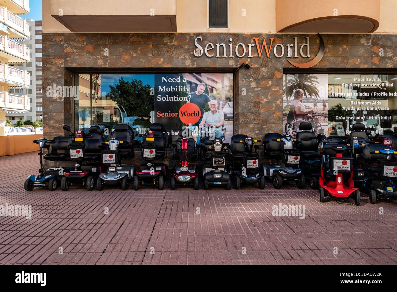 Il negozio SeniorWorld espone scooter per la mobilità. Fuengirola, Spagna, strada piastrellata, giorno di sole. Ausili alla mobilità, servizi di noleggio, assistenza agli anziani, Foto Stock