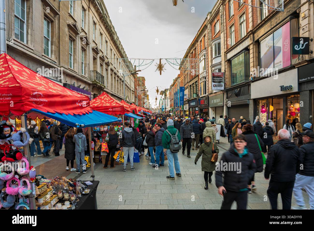 Henry Street Dublin è ricca di negozi, bancarelle colorate e luci festose in una vivace giornata di shopping. Foto Stock