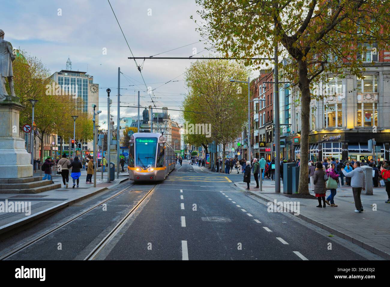 Il tram Luas si sposta lungo o'Connell Street con pedoni, negozi ed edifici storici e moderni misti nel centro di Dublino. Foto Stock