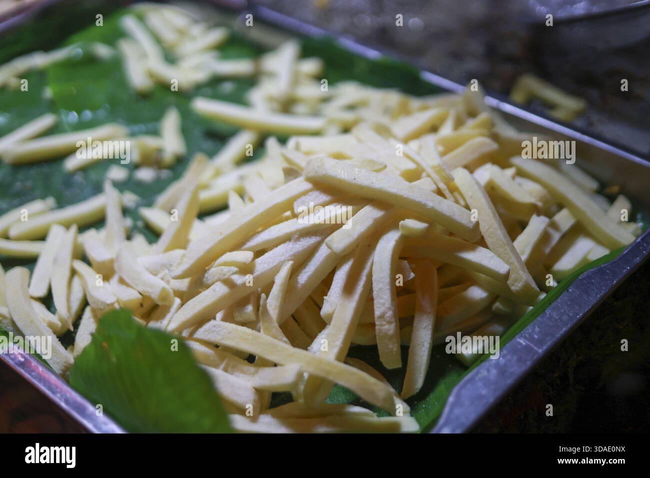 Germoglio di bambù crudo fresco, tagliato a strisce su una foglia di banana verde all'interno di un vassoio di metallo Questo ingrediente alimentare naturale è una preparazione deliziosa per cucinare Foto Stock