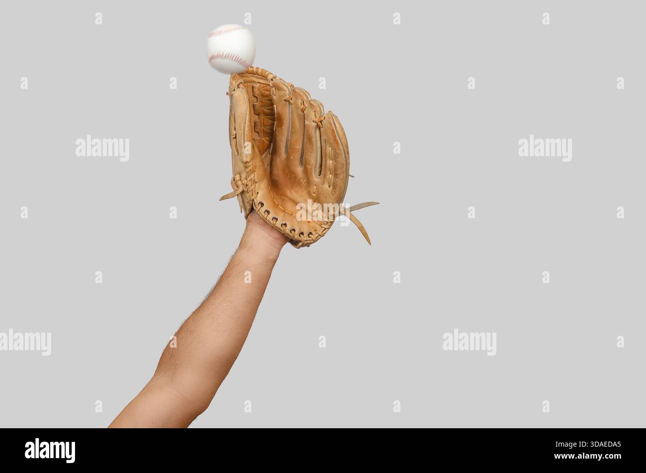 Braccio esteso con guanto da baseball aperto pronto ad intercettare palla in rapido movimento, illustrando precisione, reazione e movimento sportivo intenso. Foto Stock