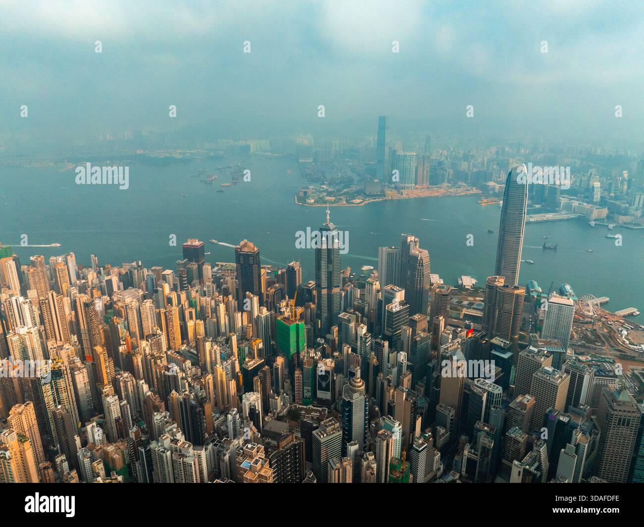 Veduta aerea dei grattacieli che penetrano nella nebbia, rivelando un vivace skyline con l'iconica Bank of China Tower e Victoria Harbour, Hong Kong, Foto Stock