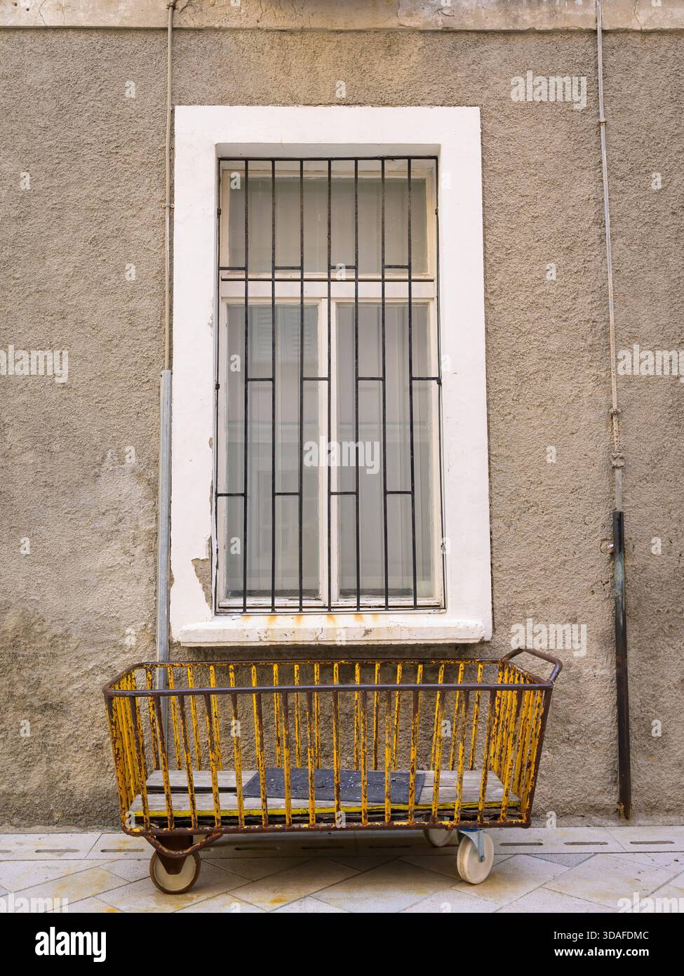 Un carrello postale giallo arrugginito si trova di fronte a una grande finestra a Cherso, Croazia, catturato in primavera con un'atmosfera vintage. Cherso Croazia Foto Stock