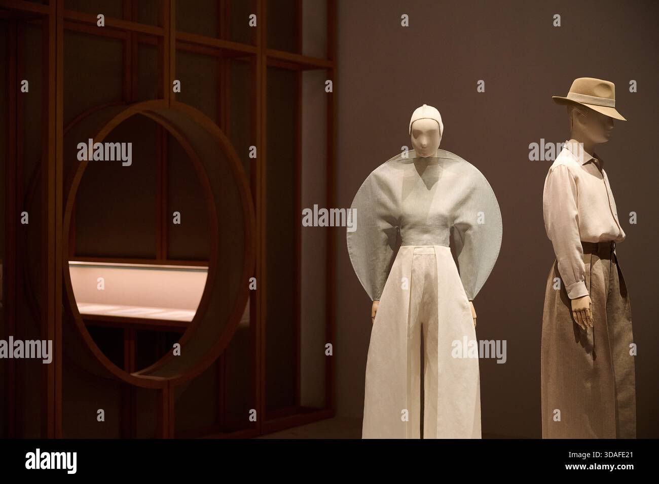 La galleria del museo della moda con doppio manichino mostra un abito rosso che scorre e una tuta marina con oggetti di scena teatrali Foto Stock